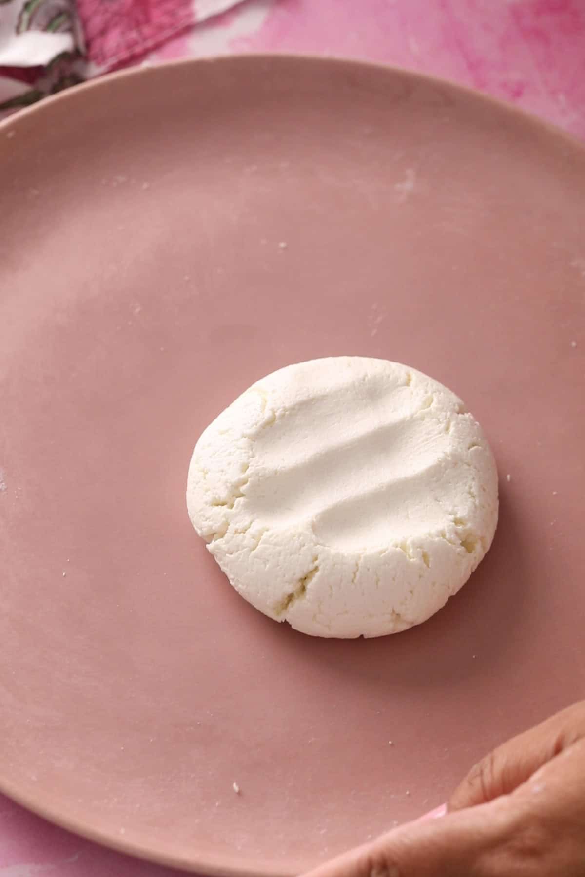 Smooth kneaded chenna is placed on a pink plate.
