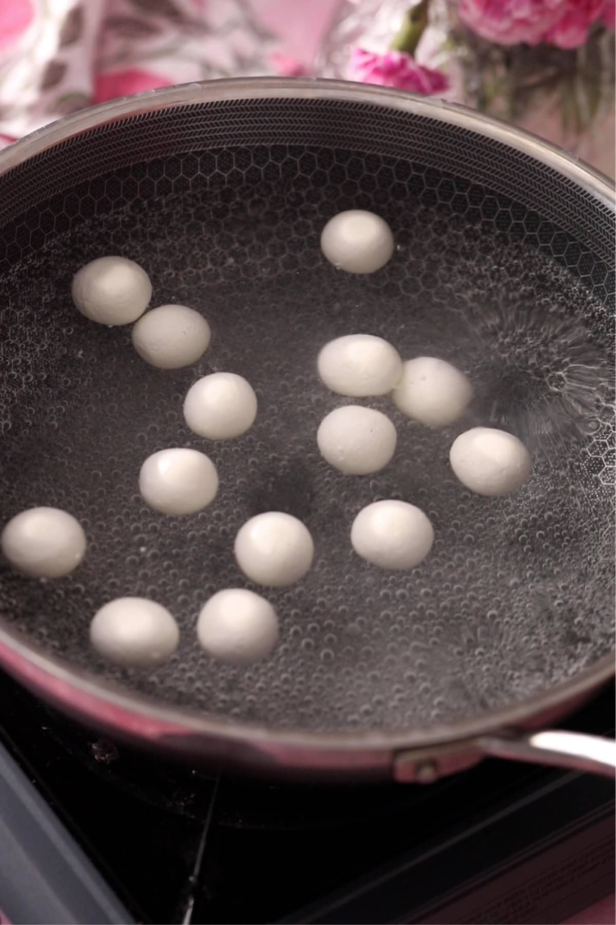 Uncooked rasgulla are placed in boiling sugar syrup.