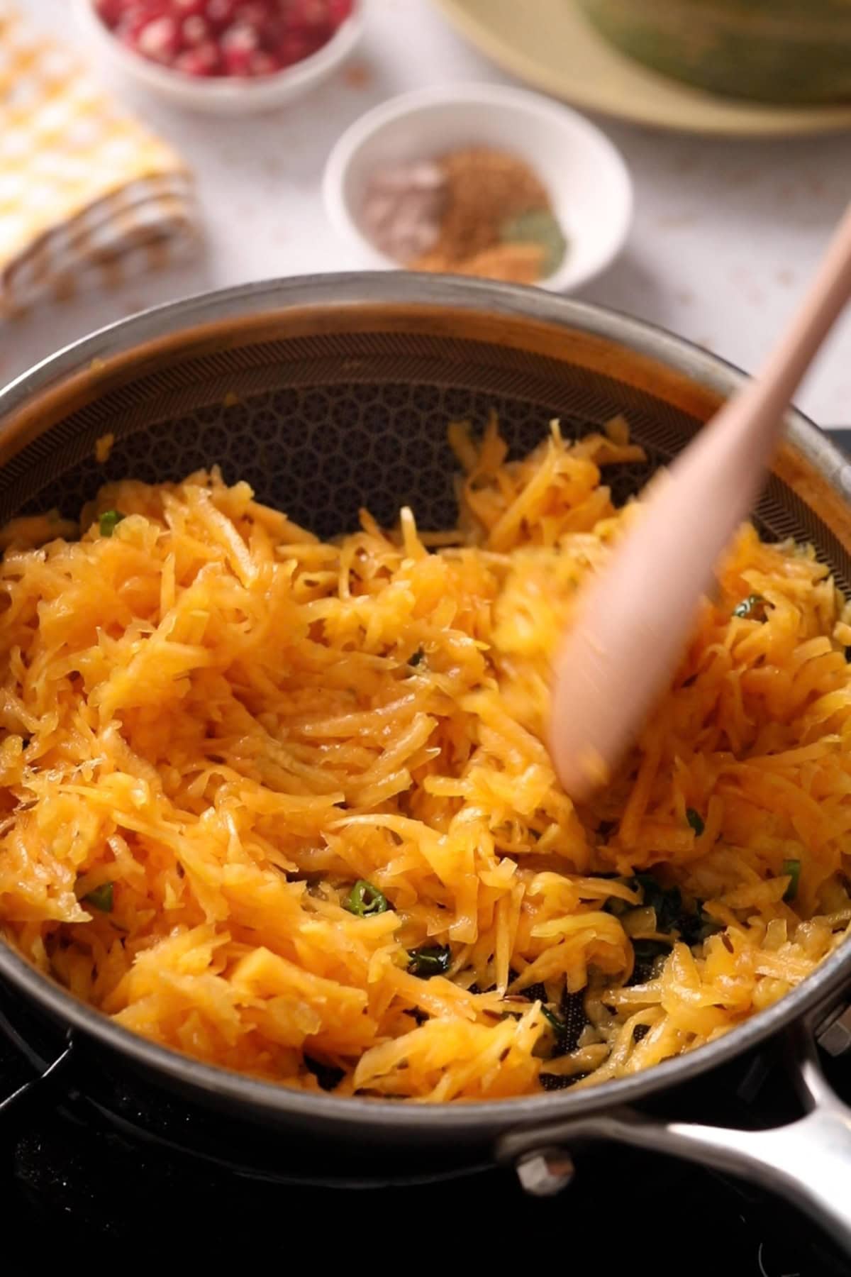Pumpkin is stirred with the aromatics in a black pan.