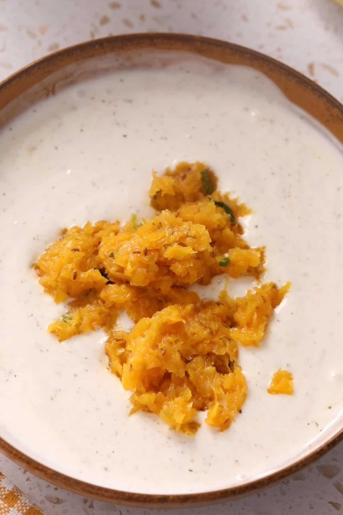 Cooked Pumpkin is added to spiced yogurt to make raita.