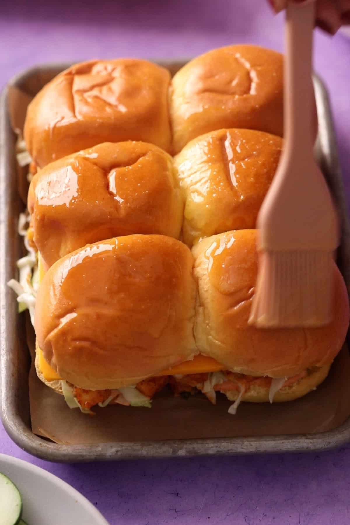 Butter is brushed on slider buns before baking.