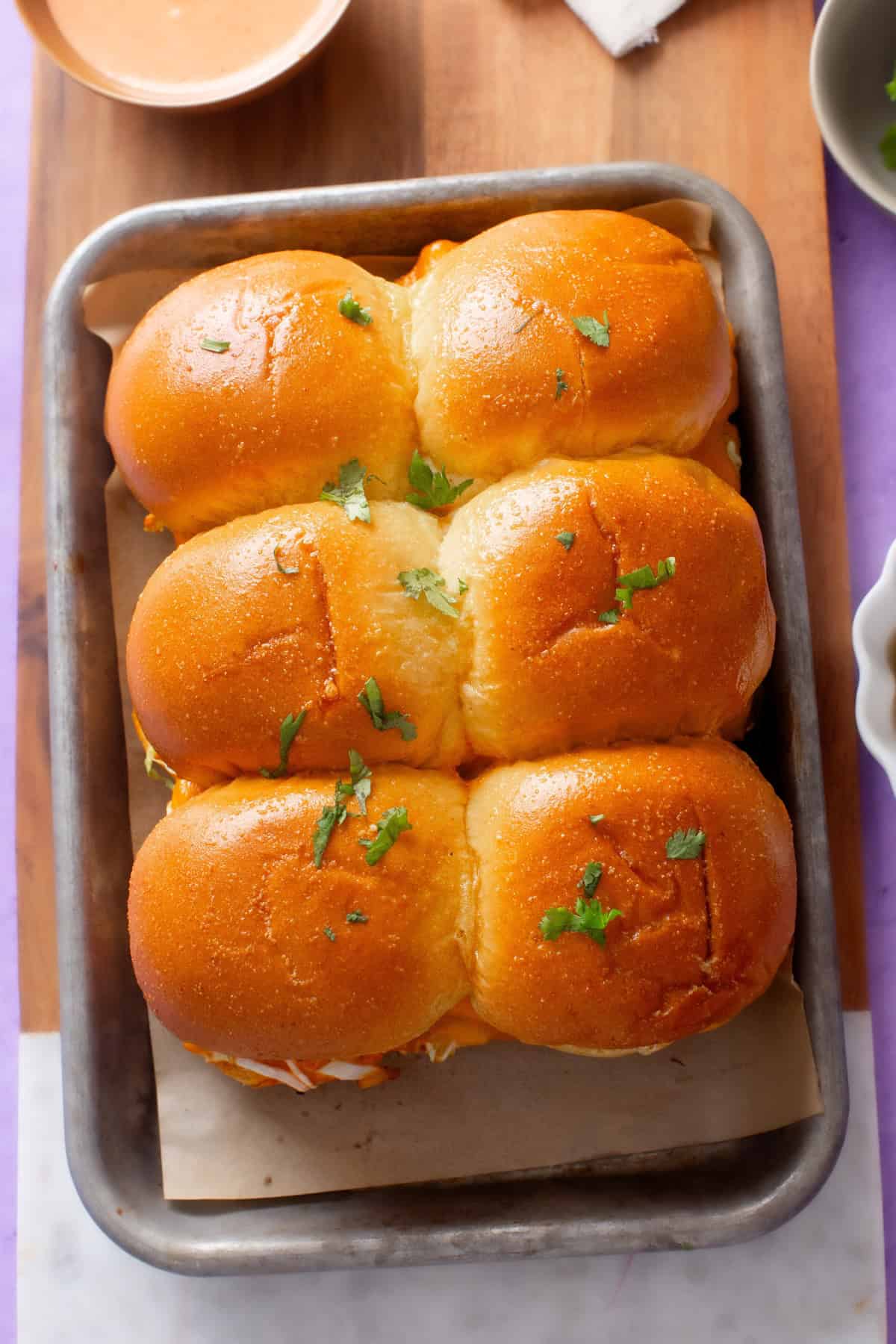 Golden looking paneer sliders are placed on a baking tray.