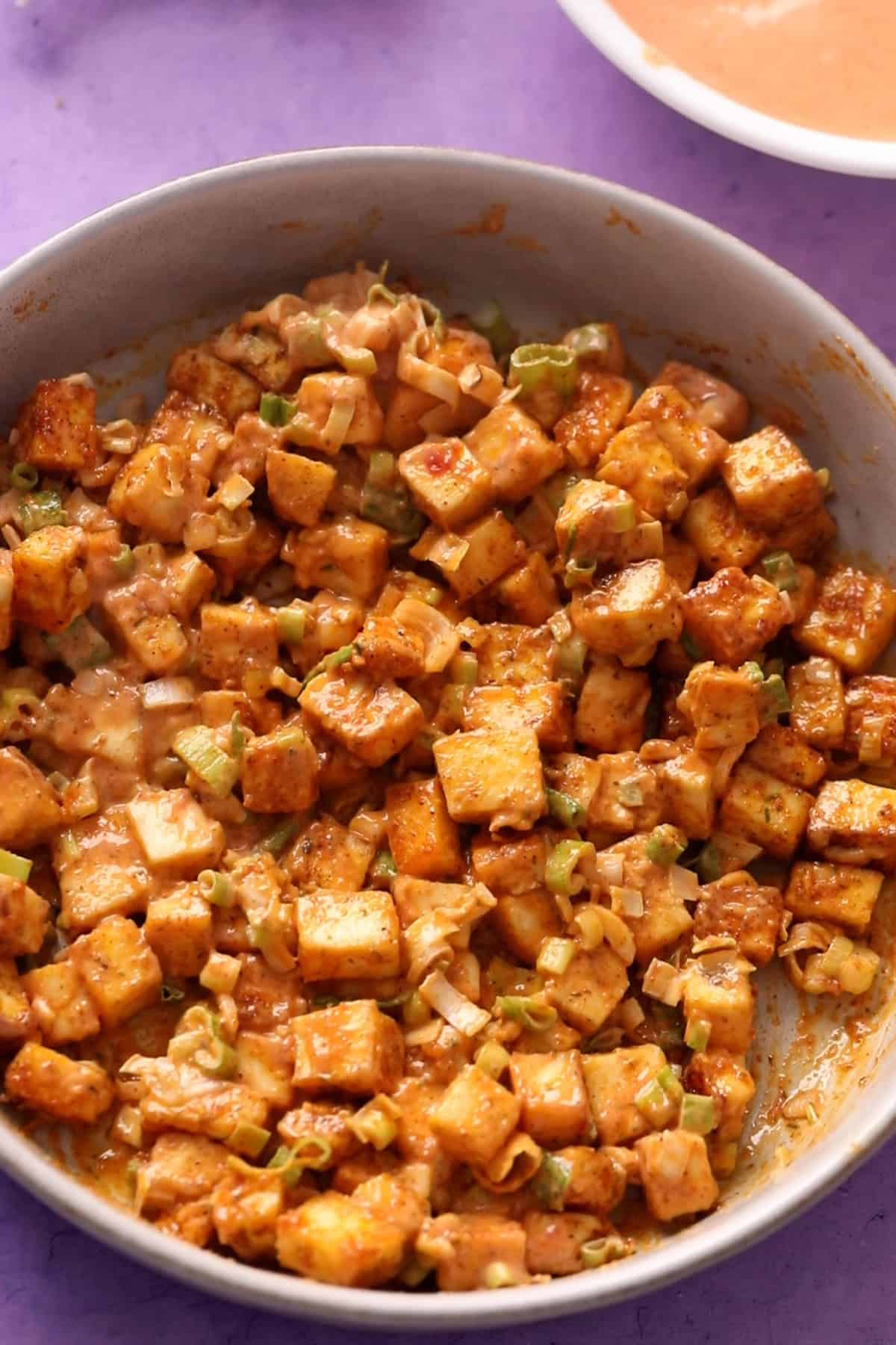 Tossed bang bang paneer in a white bowl. 