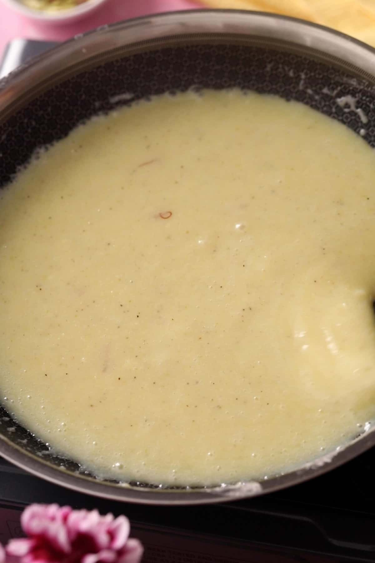 A black pan with slurry of khoya and sugar after melting.