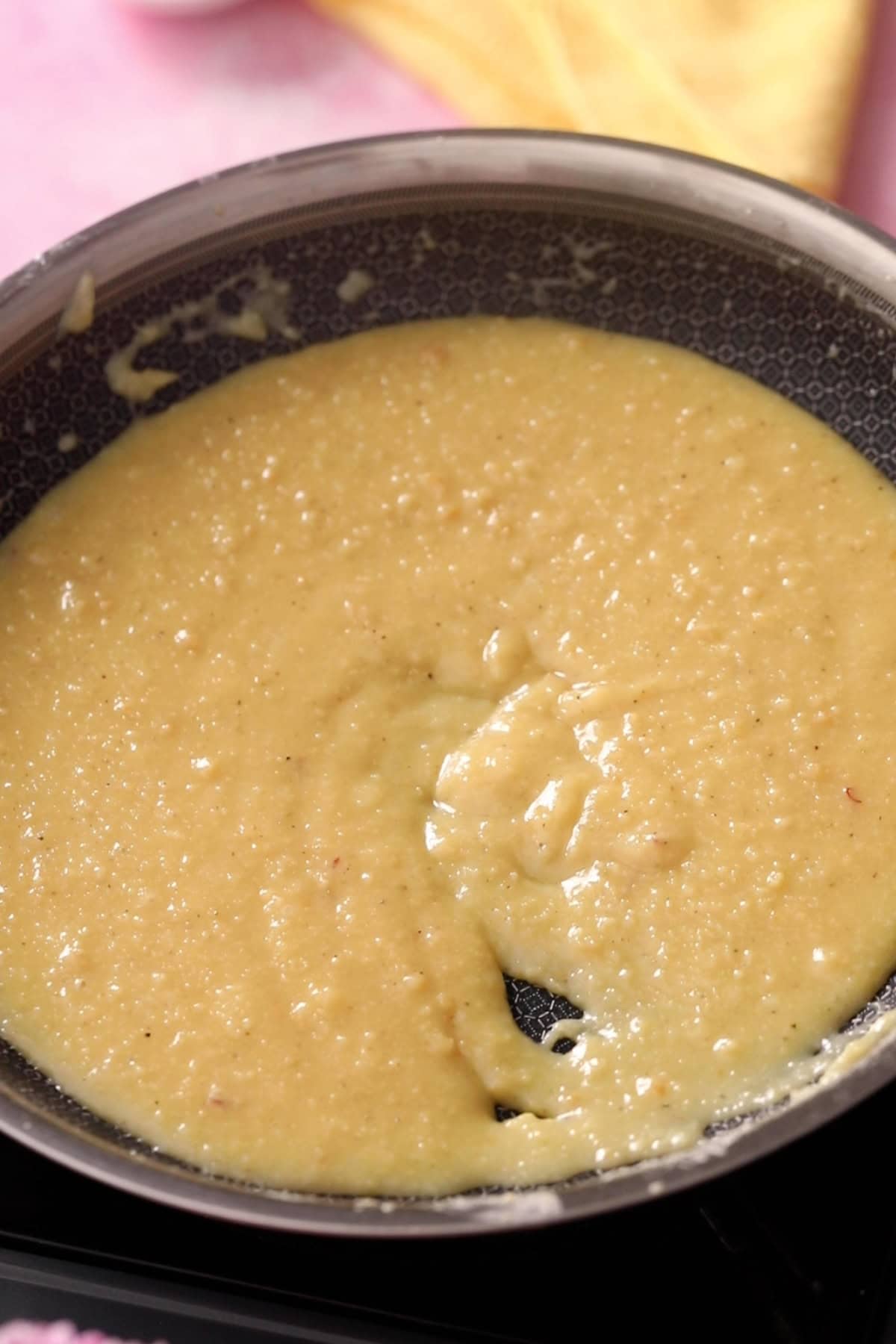 Cooked khoya and sugar mixture is turning pale saffron color.